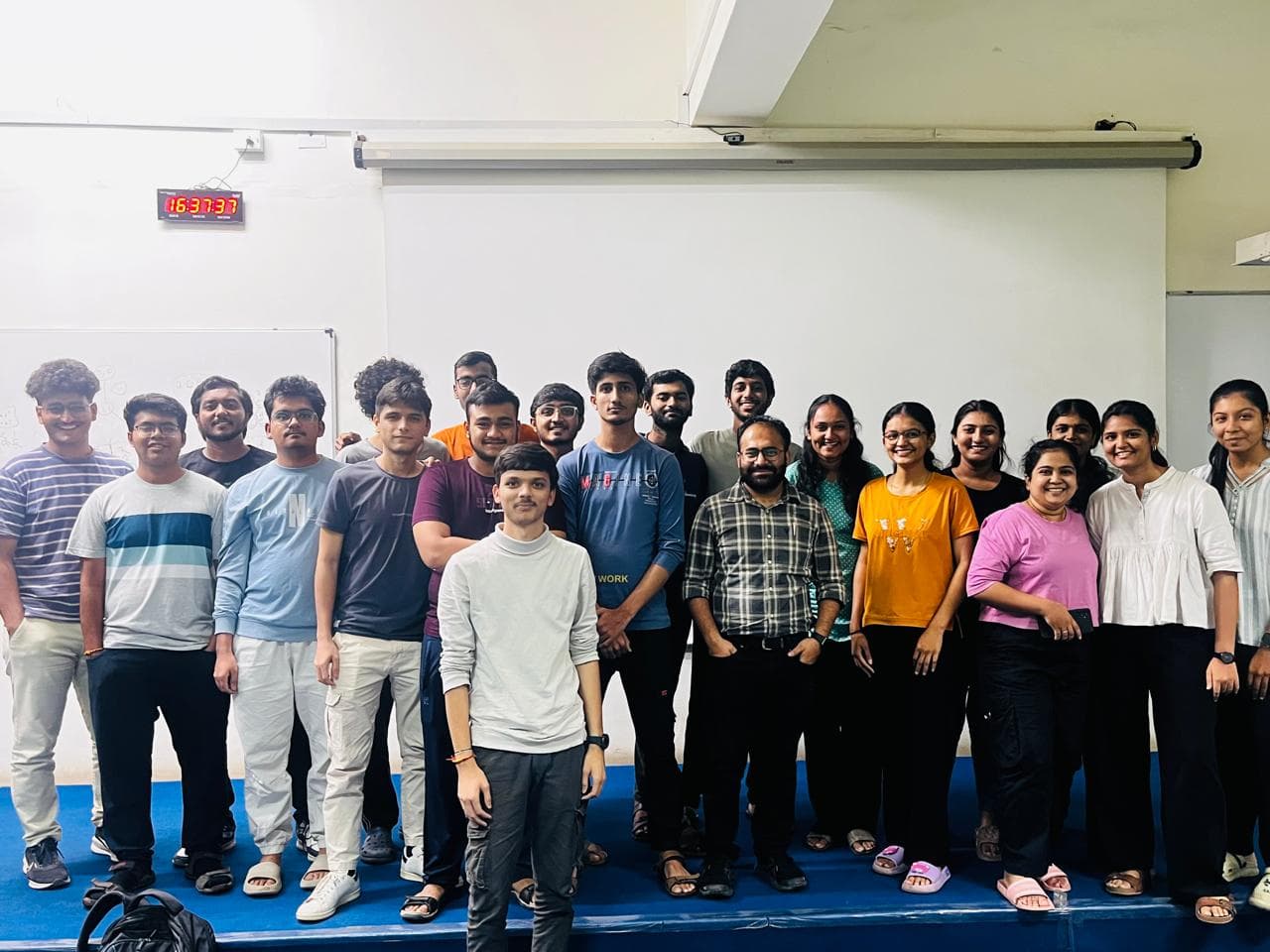 Students and their mentor posing together on a stage after class